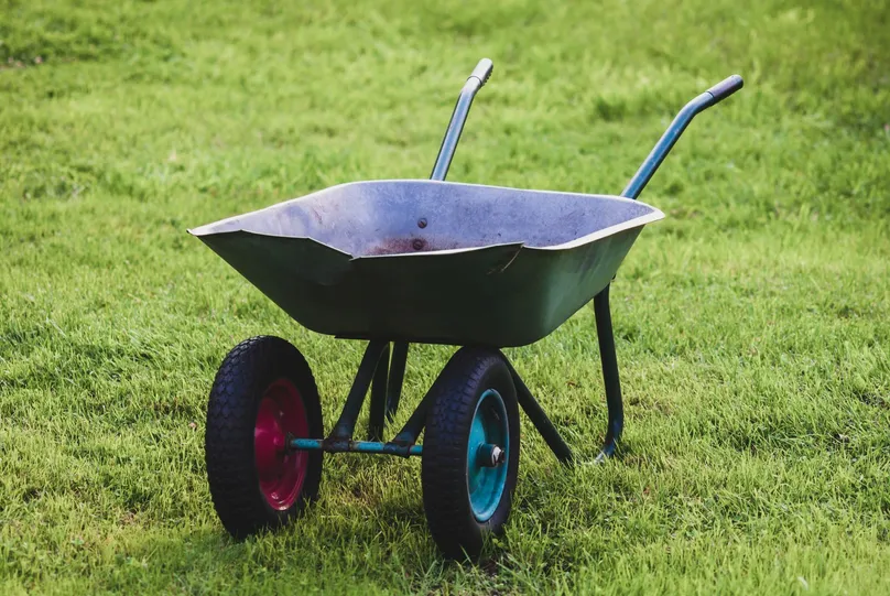 A two-wheeled wheelbarrow sitting in the grass.