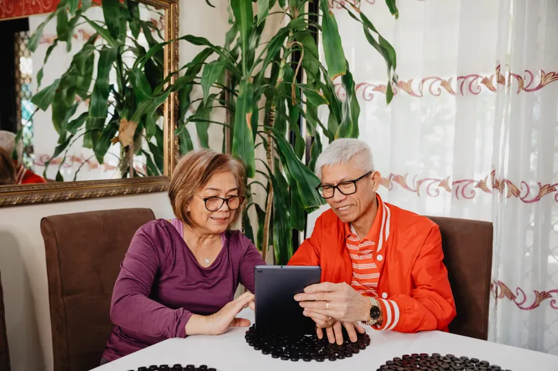 Myra and Salvador looking at LifeCurve on their tablet together at the dining room table