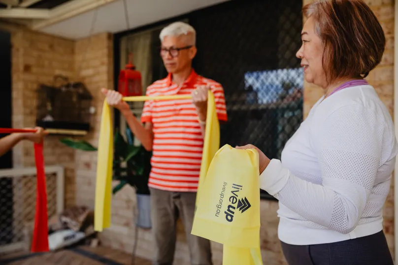Myra and Salvador practicing strengthening exercises with resistance bands in their courtyard. 