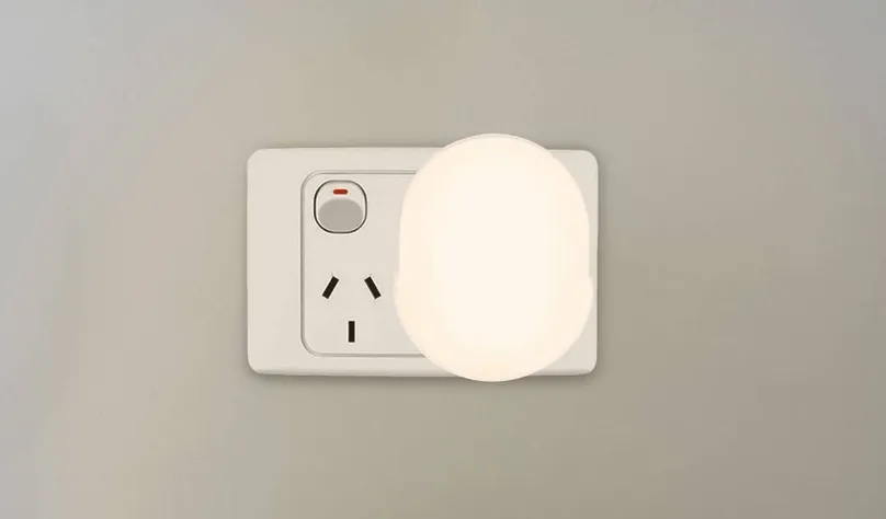 An automatic night light from Bunnings plugged into the wall and lit.