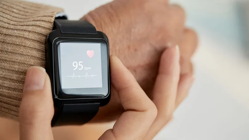 An older person checks their pulse with a smartwatch.