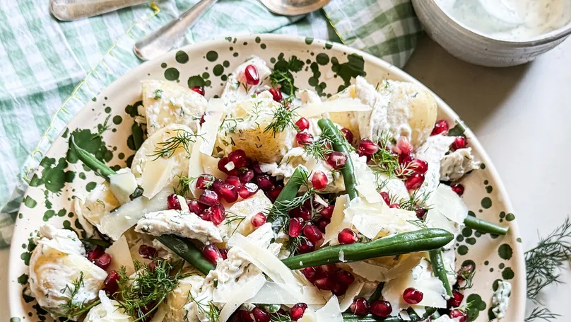 Potato, chicken, and green bean salad with dill yoghurt dressing and red pomegranate seeds.