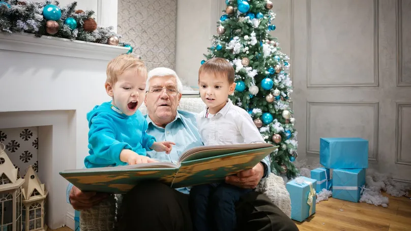Grandfather reading a picture book with his two grandsons at Christmas.