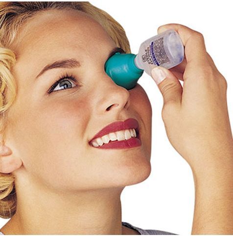 A woman using an eye drop dispenser.