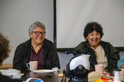 Two Aboriginal older women sit and chat about assitive technology