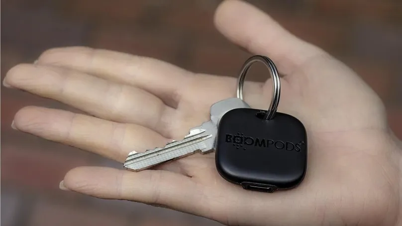 A key finder attached to a key, resting in an open hand.
