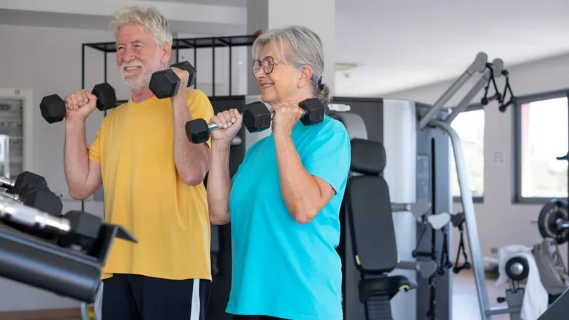 An older couple lifting dumbbell weights in the gym,