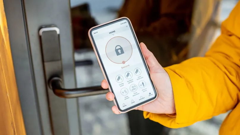 A person locking their front door with a smartphone.