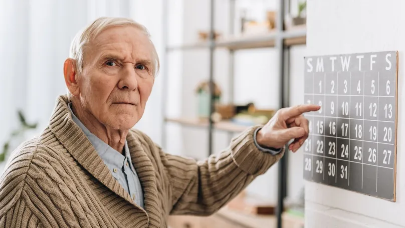 An older man pointing at the calendar.