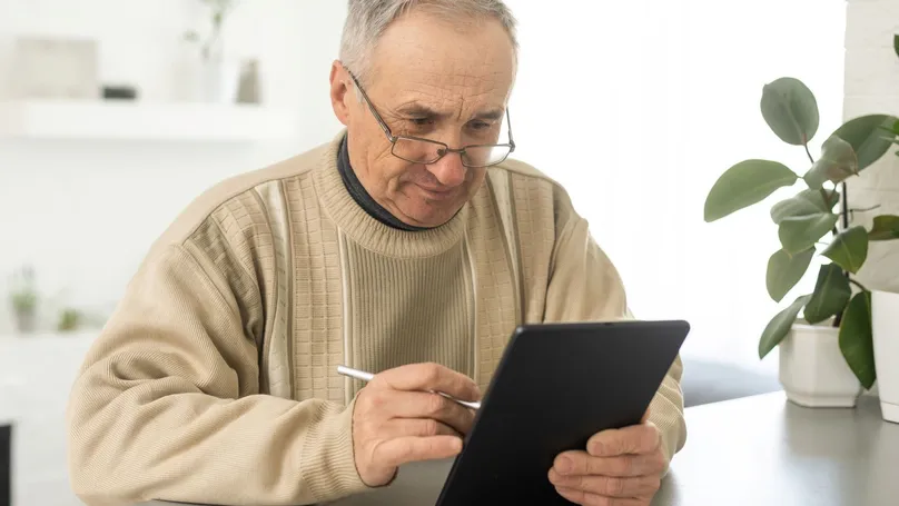 An older man using a digital notebook to write things down.