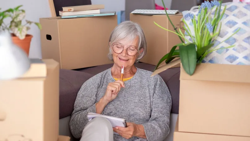 An older woman organising packing boxes while moving house.
