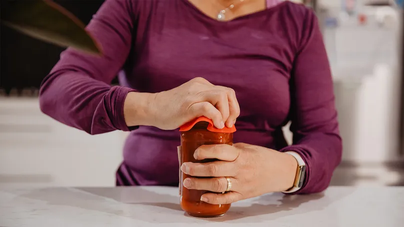 Myra uses a rubber grip-enhancer to open a jar.
