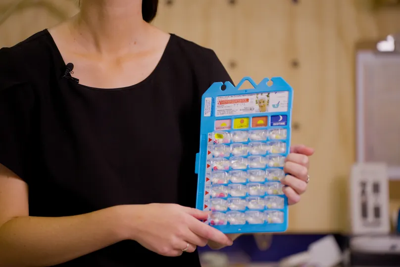 OT Rachel holds a Webster-pak medications blister pack for demonstrating at Indigo's assistive technology display centre.