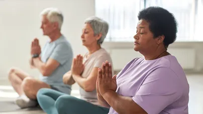 Older people meditating in lotus position with eyes closed.