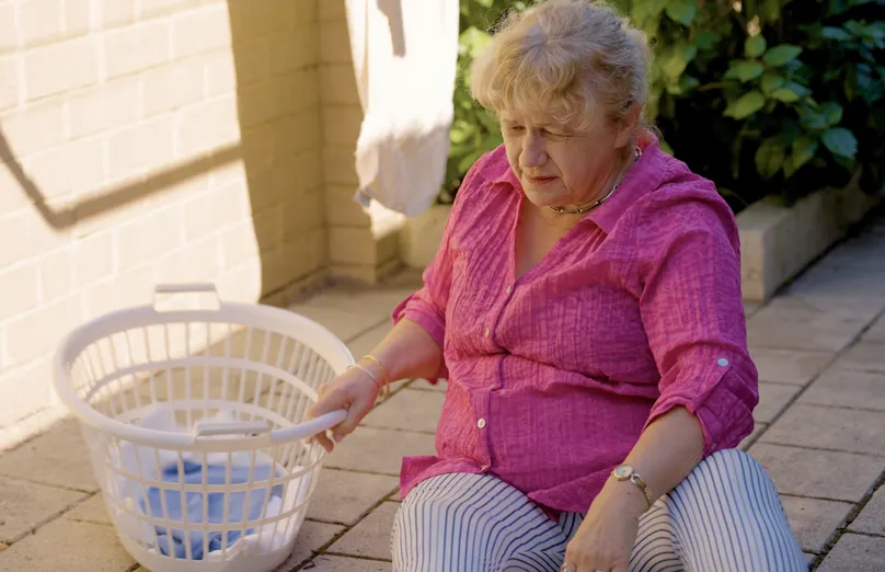 Older woman sitting on the garden floor.