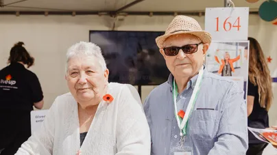 An older couple wearing poppies on their shirt lapels, in honour of ANZACs.