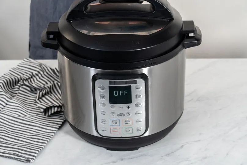 A pressure cooker on the kitchen bench turned off.