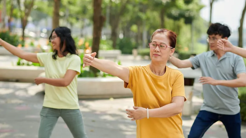 People of varying ages doing Tai Chi in the park.