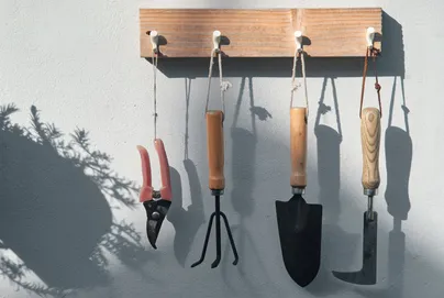 Tools hanging by rope handles on hooks along a board.