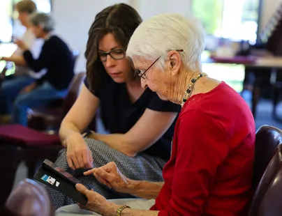 Volunteer showing iphone to student at Switched on seniors group.