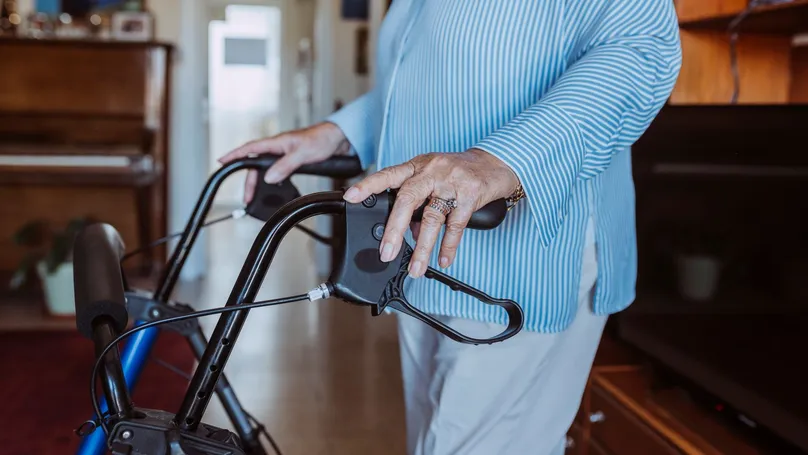 Older woman using walking aid in her home.