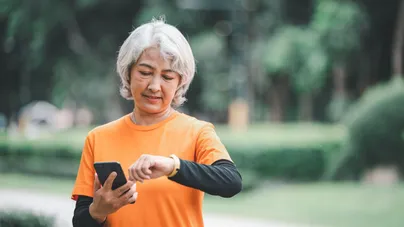 A woman exercising in the park checking her smartwatch health monitor. 