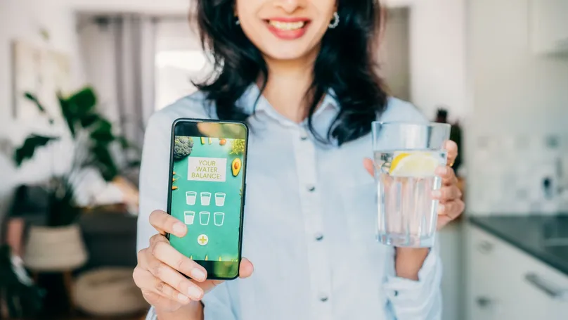 A woman using a mobile app to keep track of how many glasses of water she's drunk today.