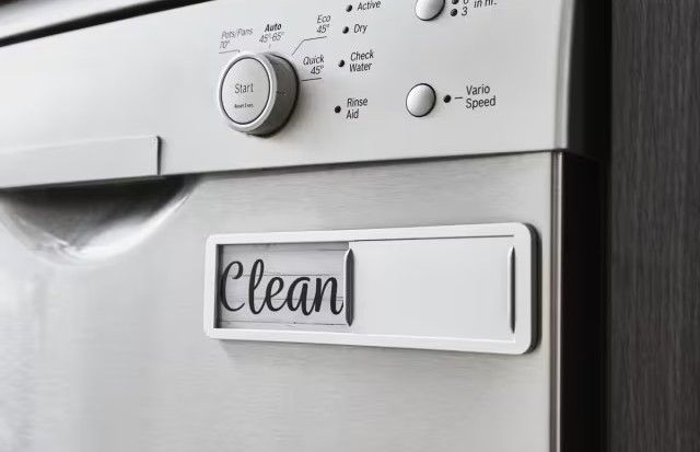 A magnetic sign on a dishwasher that says 'clean'.
