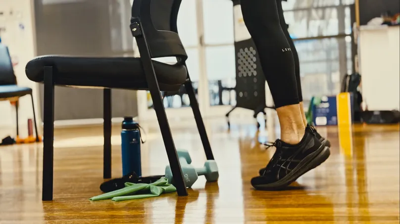 Kamilla Haufort demonstrating a calf raise with both feet, lifting her heels and standing on the balls of her feet.