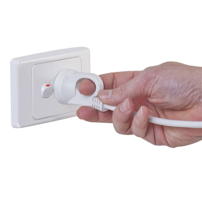 A wall plug with pull loop being pulled out by its loop.