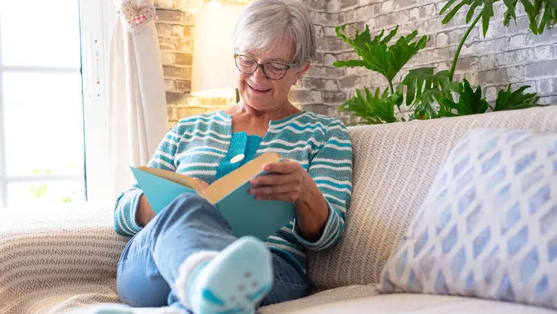 Woman relaxing with a fun book on the couch.